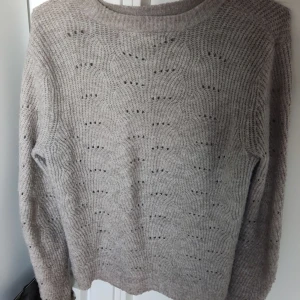 Beige stickad tröja - Mysig beige stickad tröja med ett diskret mönster. Perfekt för kyliga dagar med sin varma och bekväma passform. 