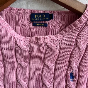 Rosa stickad tröja från Polo Ralph Lauren - Säljer en superfin rosa stickad tröja från Polo Ralph Lauren i pima bomull. Den har ett klassiskt flätmönster och en liten blå logga på bröstet. Perfekt för både höst och vår! 💖