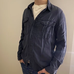 Mörkblå overshirt - Säljer en snygg mörkblå overshirt från Zara. Den har en klassisk krage och två bröstfickor med knappar. Perfekt till hösten eller våren!