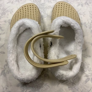 Beige tofflor med fuskpälsfoder - Mysiga beige tofflor med vit fuskpäls på insidan. Perfekta för att hålla fötterna varma under kalla dagar. De har en perforerad ovansida för ventilation och en robust sula för bra grepp. Perfekta för inomhusbruk!       Storlek kvar 41,42 och 44                              Tjocka fleece inuti, rekommenderar att välja 2 Stlk större än som är i vanlig storlek, till exempel storlek 42 passar som är Stlk 40 i vanligt storlek 