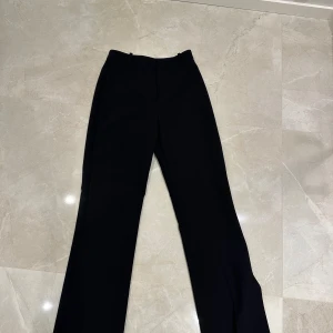 Svarta kostymbyxor från Zara - Snygga svarta kostymbyxor från Zara i storlek S. De har en klassisk och stilren design med hög midja och raka ben. Perfekta för både kontoret och festligare tillfällen. Tillverkade i ett bekvämt material som ger en elegant look.