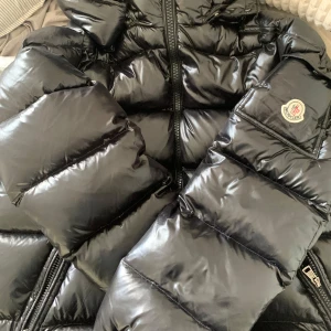 Moncler Maya Pufferjacka - Köpte jackan på plick och den är i väldigt bra skick utan defekter.❤️ (ingen NFT). Billigare pris hittar ni inte så först till kvarn. Skicka för mer info. Luva medföljer!⚠️⚠️1:1⚠️⚠️ (unisex) passar till både kille/tjej