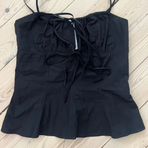 Svart axelbandslös topp Zara knytningar - Snygg svart axelbandslös topp med knytning fram. Aldrig använd. Storlek 40 men passar även en 38.