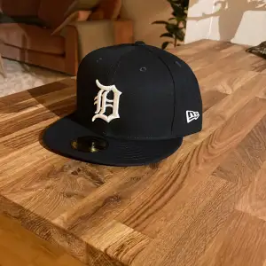 Säljer en snygg svart keps från New Era, modell 59FIFTY. Den har en broderad vit bokstav på framsidan och MLB-logga baktill. Perfekt för både vardag och sportiga tillfällen. Kepsen är helt ny och aldrig använd.      Pris går att diskutera 