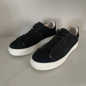 Svarta sneakers i mocka - Snygga svarta sneakers i mocka med vit sula. Svarta selected homme sneakers i stl 43. Köpta för 1200 kr på nlyman. Mycket bra skick, det ändå är att där är några fläckar på insidan av höger skon och ett pyttelitet hål på högra skon, kan skicka bild på det, men inget av det  syns typ. 