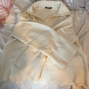 Vit stickad tröja från Gina Tricot - Mysig vit stickad tröja från Gina Tricot i storlek L. Perfekt för kyliga dagar med sin mjuka och varma känsla. Tröjan har en klassisk design med ribbade muddar vid ärmslut och nederkant. Passar både till vardags och lite finare tillfällen.