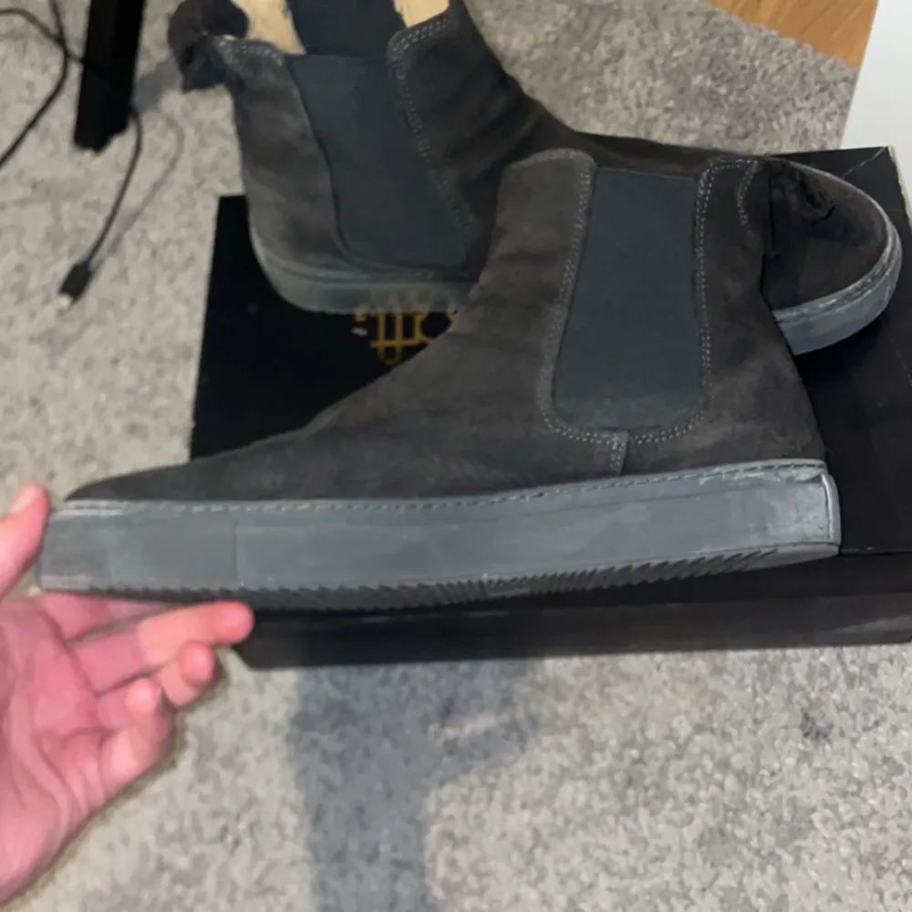 Säljer ett par snygga svarta Chelsea boots i mocka. De har en klassisk design med elastiska paneler på sidorna för enkel på- och avtagning. Perfekta för både höst och vår, och de ger en stilren touch till vilken outfit som helst. Skorna är i bra skick och redo för nya äventyr!. Skor.