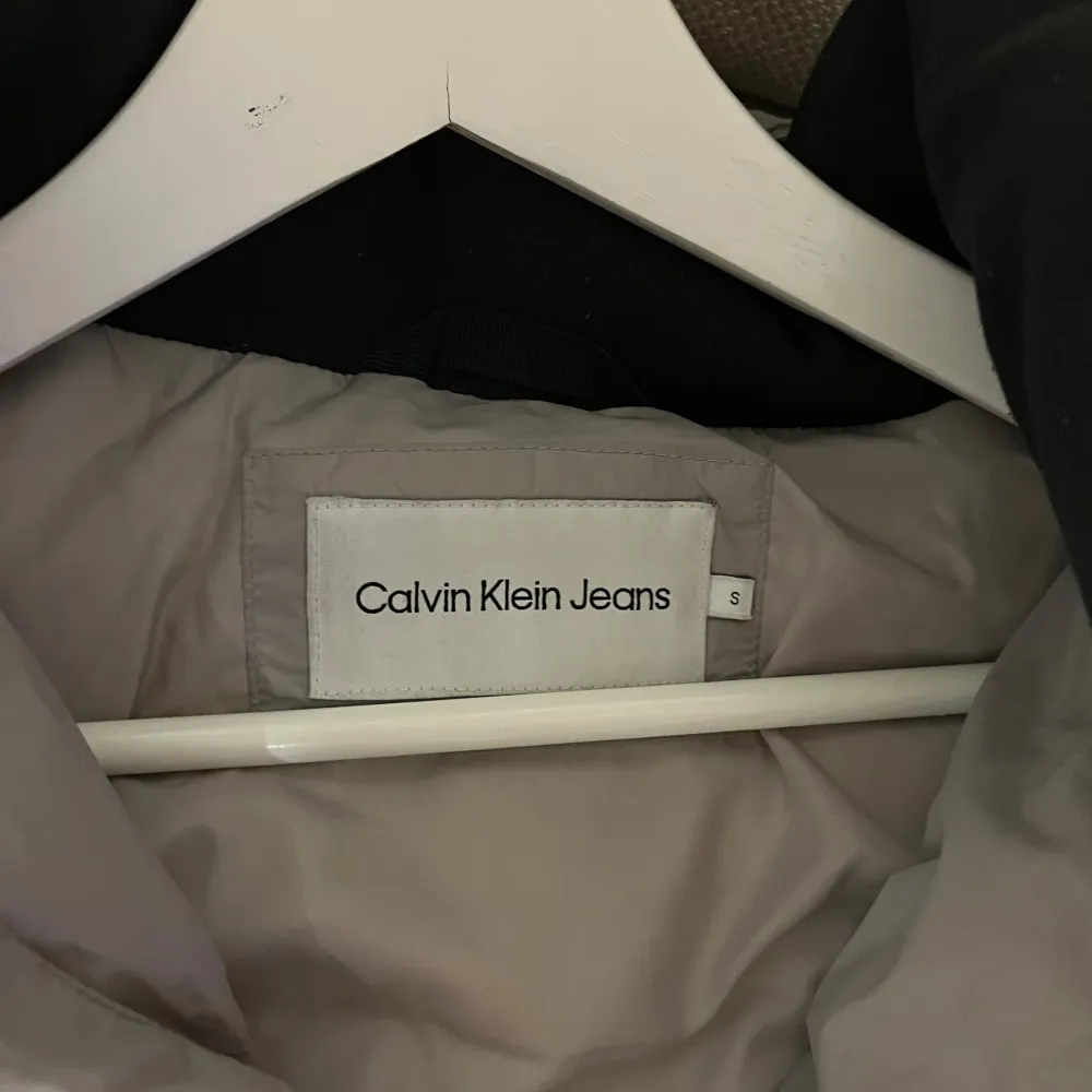 Säljer en snygg och varm grå dunjacka från Calvin Klein Jeans. Jackan har en stilren design med dragkedja och två praktiska fickor framtill. Perfekt för kalla vinterdagar. Den är i mycket bra skick och har en normal passform. Nypris-2600 (kvitton finns) mitt pris 1800. . Jackor.