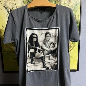 Grå t-shirt med tryck från Limitato - Säljer en grå t-shirt från Limitato i storlek S. Obs! Litet hål vid etiketten, ett stygn vid axeln, därav priset. Den har ett coolt svartvitt tryck på framsidan som ger en retro känsla. Perfekt för en avslappnad stil. T-shirten är kortärmad och i bra skick. Passar perfekt till jeans eller shorts!