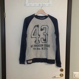 Grå och marinblå sweatshirt med tryck - Säljer en cool grå och marinblå sweatshirt från Kids by Lindex. Den har ett stort tryck med siffran 43 och texten 'NYC Madison Square 7th Ave. W.31st'. Perfekt för en avslappnad stil och passar bra till jeans. Tröjan är i bra skick och redo för nya äventyr! Pris går alltid att förhandlas!