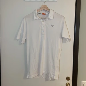 Vit pikétröja från Puma - Säljer en stilren vit pikétröja från Puma i mycket bra skick. Tröjan har en klassisk krage med knappar och det ikoniska Puma-loggan på bröstet. Perfekt för både vardag och sportiga aktiviteter. Storleken är herr M. Pris går alltid att förhandlas!