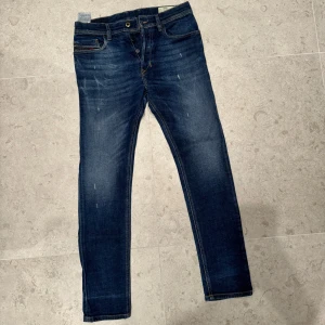 Blåa Diesel Jeans med slitningar. - Säljer ett par Diesel-jeans i storlek W30 L30, i mycket gott skick (9/10). Mörkblå färg med klassisk design och lätt användning. Hör av dig vid frågor eller om du vill ha fler bilder!
