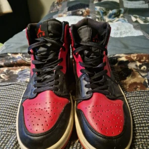 Nike Air Jordans i rött och svart - Säljer ett par klassiska Nike Air Jordans i rött och svart. Skorna har snörning och är i bra skick med en cool design. Perfekta för både vardag och fest! 🏀