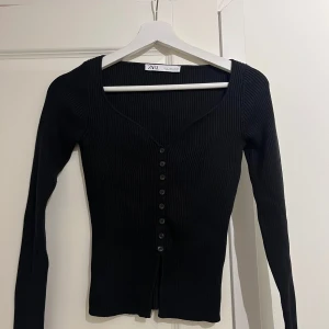 Svart tight ribbad tröja zara - Snygg svart tröja med knappar framtill och en längre slits i nederkanten. Tröjan är figursydd och har en fin ribbstickning. Använd endast 1-2 gånger💕💕