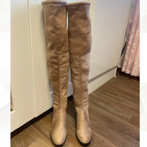 Beige overknee boots/ helt nya  - Säljer ett par nya snygga beige overknee boots. De har en stilren design med rund tå och en liten klack för extra komfort. Perfekta för höst och vinter, och de har en knytning baktill för justerbar passform. Använd dem till både vardags och fest för en chic look!