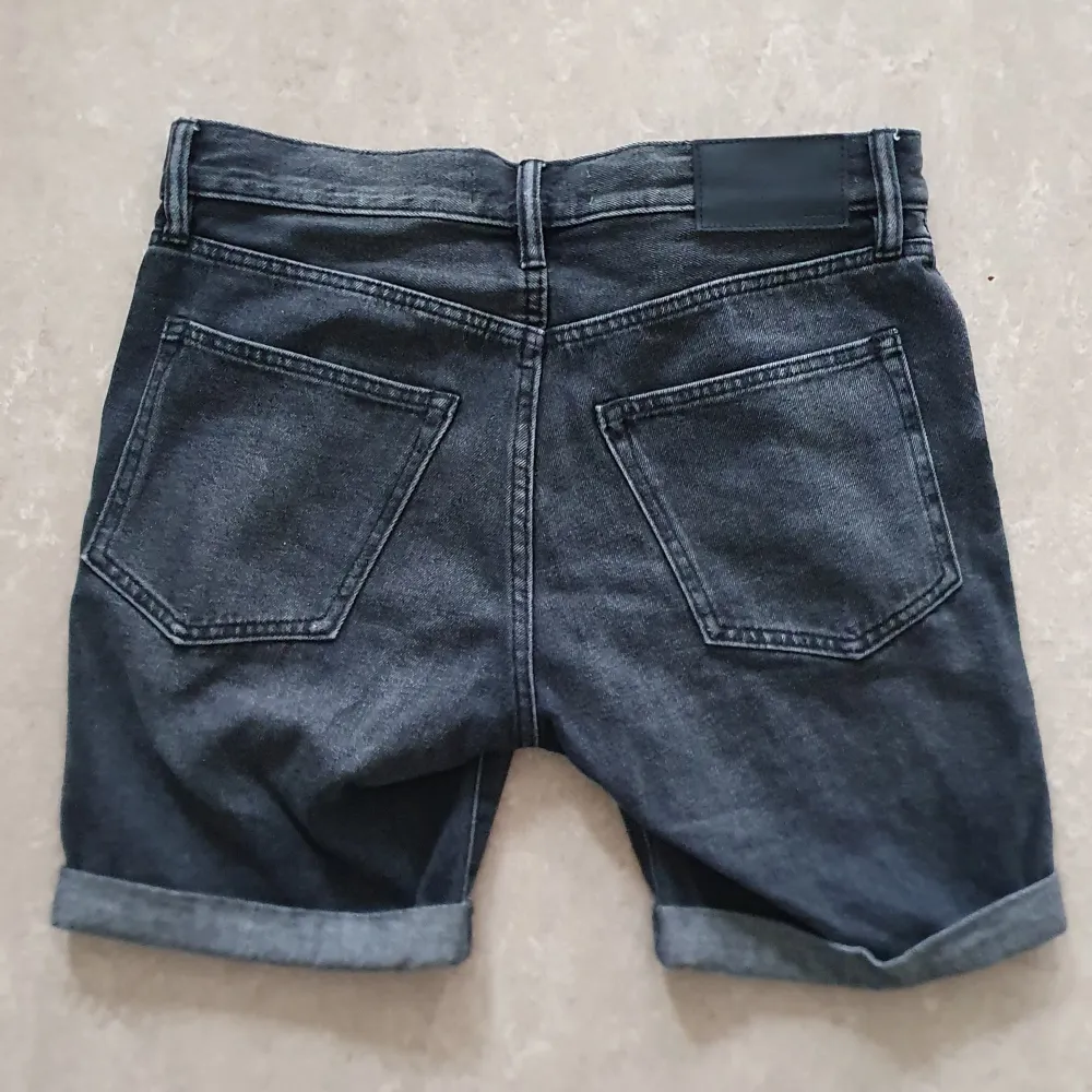 Snygga svarta jeansshorts från H&M med en cool slitning på framsidan. De har en klassisk femficksdesign och knappar i gylfen.. Shorts.