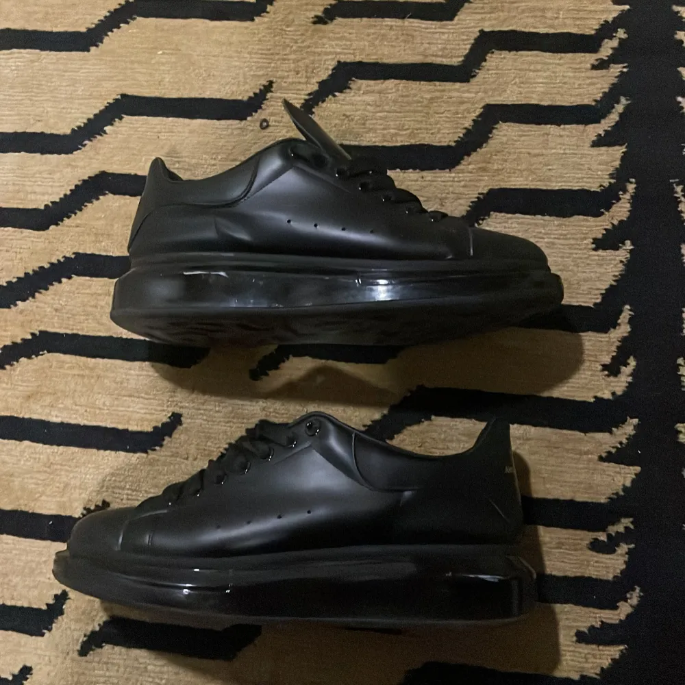  Alexander McQueen's Larry sneakers feature an exaggerated yet minimalistic oversized silhouette. Crafted from smooth leather with an elevated and transparent rubber sole, they feature the brand's logo on the heel counter and tongue. Size 46 fit 45.. Skor.