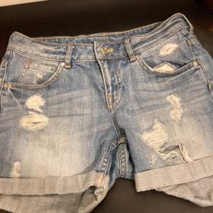 Säljer ett par coola blå jeansshorts från H&M i storlek 34. De har en snygg slitning och uppvikta ben för en avslappnad look. Perfekta för sommardagar eller festivaler. De är i bra skick och redo för nya äventyr! 🌞