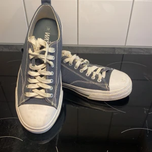 Blå sneakers med vita detaljer - Säljer ett par blå sneakers från Warp i storlek 41. De har vita snören och en vit sula som ger en klassisk look. Perfekta för vardagsbruk och passar till det mesta. Lite använda men i bra skick!