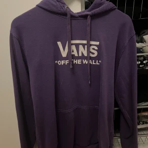 Lila hoodie från Vans - Säljer en lila hoodie från Vans med deras klassiska 'Off The Wall' tryck på framsidan. Den är superbekväm, Har en stor ficka fram och justerbar huva. Katt finns i hemmet men den är tvättad och rollad innan den skickas