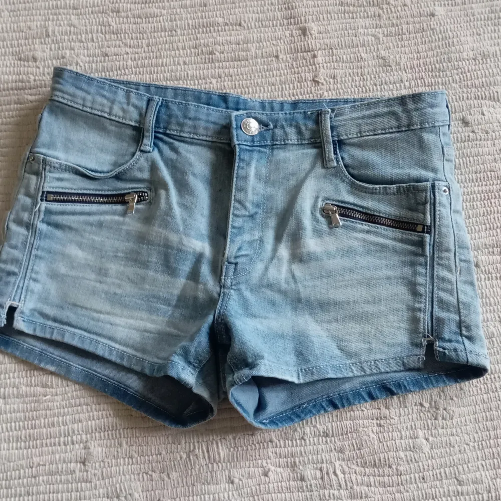 Säljer ett par ljusblå jeansshorts från &Denim. De har en snygg slitning och två dragkedjor framtill för extra stil. Perfekta för sommardagar!. Shorts.