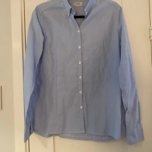 Ny ljusblå skjorta i oxfordbomull i strl 42 från Boomerang, modell latitud shirt - Ny ljusblå skjorta i oxfordbomull i strl 42 från Boomerang, modell latitud shirt.  Ny, aldrig använd.  Mått Över bröstet: ca 52 cm Längd från axeln och ner: ca 68 cm  100% bomull   Kommer från ett djur och rökfritt hem.