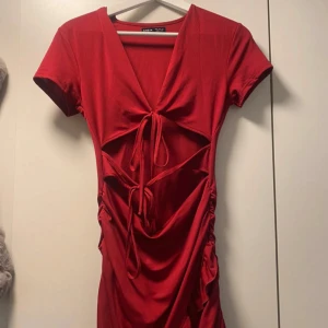 Röd omlottklänning från Missguided - Snygg röd omlottklänning från Missguided i storlek S. Klänningen har en v-ringad design med knytning framtill och korta ärmar. Perfekt för festliga tillfällen! Materialet är mjukt och stretchigt för en bekväm passform.