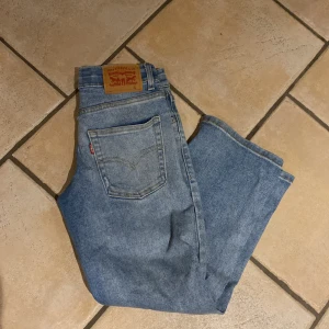 Blå jeans från Levi's - Säljer ett par klassiska blå jeans från Levi's med en loose tapered passform. De har en midwaist design och är tillverkade i jeansmaterial. Perfekta för en avslappnad stil.