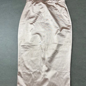 Beige kjol från NLY One - Elegant beige kjol från NLY One i en slät och glansig finish. Kjolen har en smickrande tight passform och en diskret slits baktill för extra rörelsefrihet. Perfekt för att skapa en stilren look.