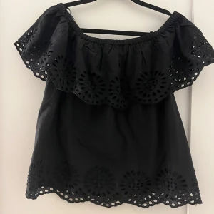 Svart offshoulder topp från Vila - Säljer en snygg svart offshoulder topp från Vila med vackra broderade detaljer. Toppen har korta ärmar och en luftig passform, perfekt för varma dagar. Den elastiska kanten ger en bekväm passform. Passar utmärkt till både jeans och kjol.
