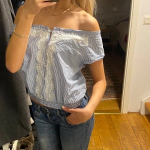 Blå- och vitrandig offshoulder-top - Säljer en söt blå- och vitrandig offshoulder-top med spetsdetaljer framtill 😍😍.  Obs Toppen är köpt på barnavdelningen (storlek 146/152)