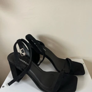 Svarta klackskor från Glamorous - Snygga svarta klackskor från Glamorous med en elegant design. Skorna har en fyrkantig tå och en justerbar rem med spänne runt ankeln. Perfekta för att ge en ren touch till din outfit. OANVÄNDA💞 Nypris: 400kr