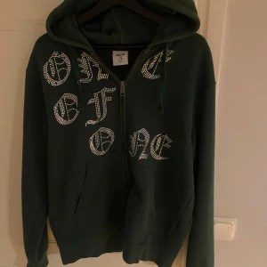 Mörkgrön hoodie från One of One - Säljer en mörkgrön hoodie från One of One med dragkedja och huva. Tröjan är limiterad från ett drop. Strl M