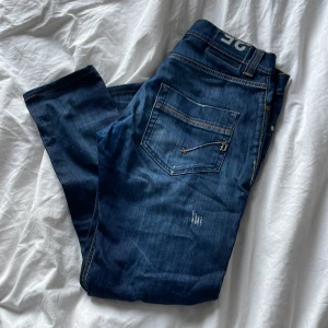 Dondup - Snygga blå jeans med slitningar och knappgylf. De har en klassisk femficksdesign och kontrastsömmar. Perfekta för en vanlig vardag eller fest.