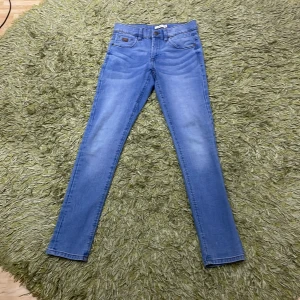 Blå jeans från Name It - Snygga blå jeans från Name It i storlek 152. De har en klassisk femficksdesign och en bekväm passform. Perfekta för vardagsbruk och kan enkelt matchas med olika toppar.