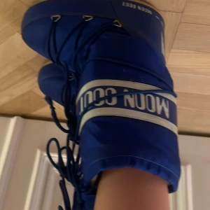 Blå Moon Boots - Säljer ett par blå Moon Boots med snörning. Perfekta för vintern med sin unika design och varma passform. 