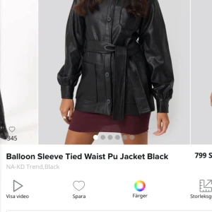 Svart PU-jacka med knytband från NA-KD - Snygg svart PU-jacka från NA-KD med ballongärmar och knytband i midjan. Jackan har knappar framtill och en stilren design som passar perfekt för en trendig look. Den är ganska tunn och passar därför bra vid våren!