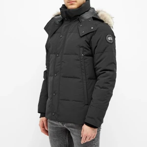 Canada Goose black label - Säljer en svart dunjacka från Canada Goose med avtagbar huva och pälsdetalj. Jackan har en hög krage, dragkedja och knappar framtill samt en broderad logotyp på ärmen. Perfekt för kalla vinterdagar.