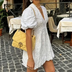 Vit klänning med puffärmar - Säljer en söt vit klänning med puffiga kortärmar och v-ringning. Klänningen har ett vackert broderat mönster och en kort längd som ger en fräsch look. Perfekt för sommarens alla tillfällen!