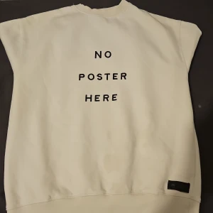 Vit sweatshirt med text - Säljer en vit sweatshirt med texten 'NO POSTER HERE' tryckt på framsidan. Tröjan har långa ärmar och ribbade muddar vid ärmslut och nederkant. Perfekt för en avslappnad stil.