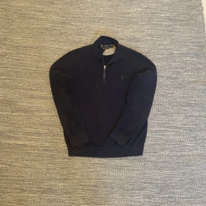 Mörkblå tröja från Polo Ralph Lauren - Säljer en stilren mörkblå tröja från Polo Ralph Lauren med dragkedja vid halsen. Tröjan har långa ärmar och är tillverkad i ett mjukt material som passar perfekt för kyligare dagar. Perfekt för dig som vill ha en klassisk look.