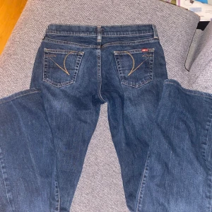Blå bootcut jeans - Snygga mörkblå bootcut jeans med klassisk femficksdesign och dekorativa sömmar på bakfickorna! Midjemått 38cm tvärs över och innerbenslängd 80cm