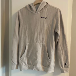 Beige hoodie från Champion (barn) - Säljer en snygg beige hoodie från Champion i storlek XL (barn). Den har en klassisk känguruficka och Champion-loggan broderad på bröstet och ärmen. Perfekt för en avslappnad stil och passar till alla årstider. Superbekväm och i bra skick! Obs storlek XL för BARN 