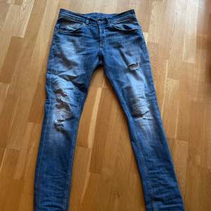 Säljer ett par snygga blå jeans från Dondup i storlek 30. De har en slim passform med slitna detaljer på framsidan för en trendig look. Perfekta för både vardag och fest! Tillverkade i Italien med hög kvalitet.