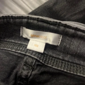 Svarta jeans från Gina Tricot - Säljer ett par svarta jeans från Gina Tricot i storlek 152. De har en klassisk femficksdesign och är i bra skick. Perfekta för vardagsbruk med en bekväm passform. Passar till både skola och fritid!
