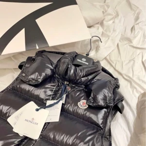 Moncler - Säljer en snygg svart dunväst från Moncler i nytt skick. Västen har en glansig finish och dragkedja framtill. Perfekt för höst och vinter, och den håller dig varm och stilren. Passar både till vardags och lite finare tillfällen, priset kan diskuteras vid snabbt köp kan mötas upp i Kalmar annars fraktas den jag kan stå för frakten. Fler bilder kan skickas via dm