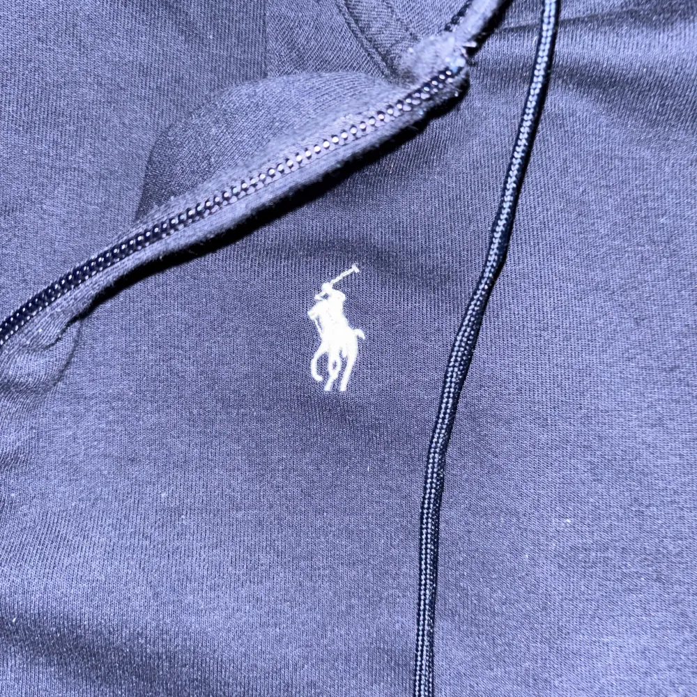 Säljer en snygg mörkblå hoodie från Polo Ralph Lauren i storlek M. Den har en dragkedja framtill och den klassiska loggan broderad på bröstet. Perfekt för höst och vår, med en skön passform och fickor för extra bekvämlighet. Huvan ger en avslappnad stil. Passar både till vardags och chillkvällar.. Tröjor & Koftor.