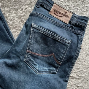 Mörkblå jeans från Jacob Cohen - Säljer ett par snygga mörkblå jeans från Jacob Cohen. De har en klassisk femficksdesign och en snygg läderpatch baktill. Perfekta för både vardag och fest! 🕺