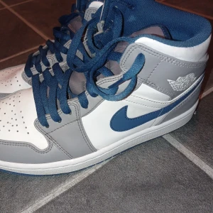 Nike Air Jordans i grått och blått - Säljer ett par snygga Nike Air Jordans i grått och blått. Skorna har en klassisk design med snörning och det ikoniska Air Jordan-märket på sidan. Perfekta för både vardag och sportiga tillfället. 10/10 skick lite smutsiga under skorna men det går att fixa. 