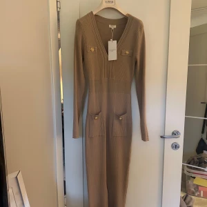 Beige långklänning köpt på Raglady  - Snygg beige långklänning Raglady. Grifoni i ribbat material. Den har en v-ringad design med långa ärmar och dekorativa knappar på bröstet och fickorna. Perfekt för höst och vinter, både stilren och bekväm! Aldrig använt därav pris lapp kvar enbart testat den 1 gång ny pris 600kr säljer den för 550kr🥰det är både storlek M/L